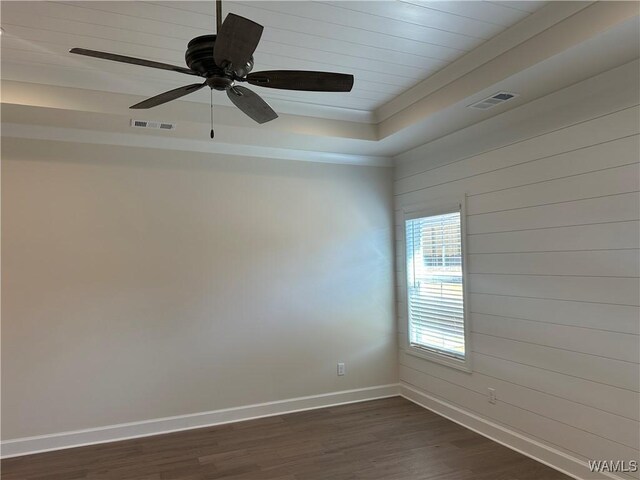 unfurnished room with a tray ceiling, ceiling fan, and dark hardwood / wood-style floors