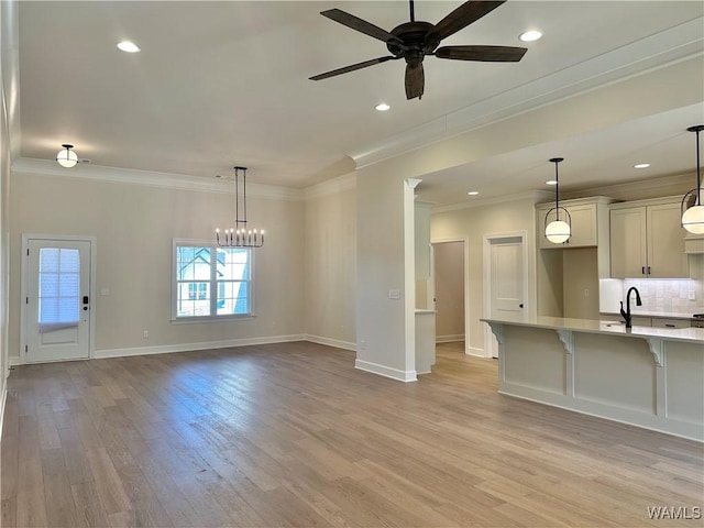 interior space with crown molding, sink, light hardwood / wood-style floors, and ceiling fan with notable chandelier