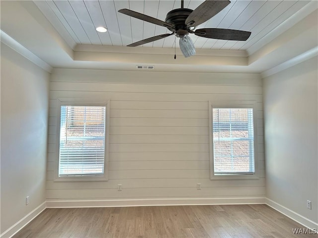 spare room with light wood-type flooring, a tray ceiling, ceiling fan, and crown molding