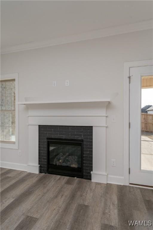 room details featuring a tiled fireplace, wood finished floors, baseboards, and ornamental molding