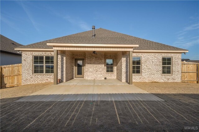 rear view of property with brick siding, a shingled roof, fence, a ceiling fan, and a patio