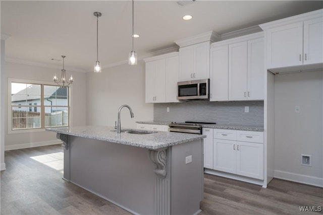 kitchen featuring a kitchen island with sink, a sink, appliances with stainless steel finishes, white cabinets, and crown molding