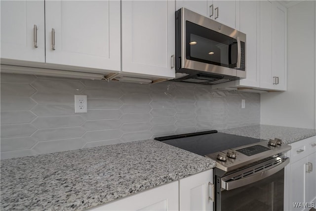 kitchen with light stone counters, appliances with stainless steel finishes, and white cabinetry