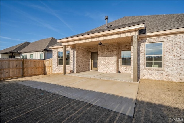 back of property with a ceiling fan, a patio, fence, roof with shingles, and brick siding