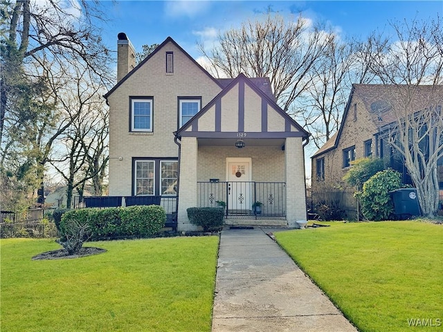 tudor home with a porch and a front yard