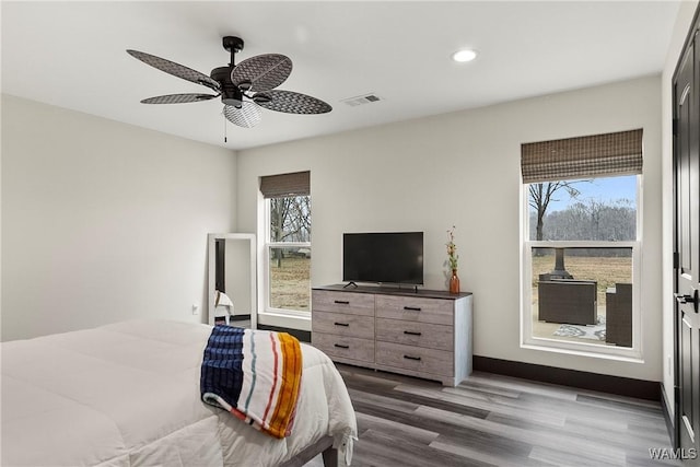 bedroom with light wood finished floors, multiple windows, visible vents, and a ceiling fan