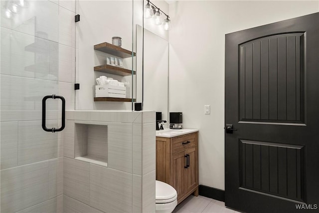 bathroom featuring a stall shower, baseboards, toilet, tile patterned floors, and vanity