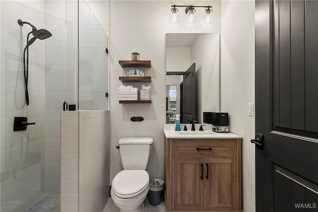 bathroom featuring toilet, a shower stall, and vanity