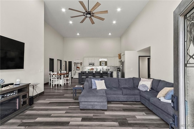 living area with dark wood-style floors, recessed lighting, a high ceiling, and a ceiling fan