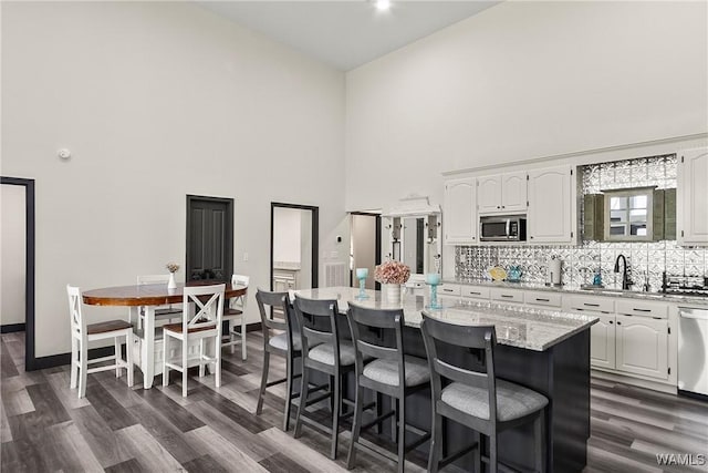 kitchen featuring appliances with stainless steel finishes, a center island, light stone counters, and white cabinets