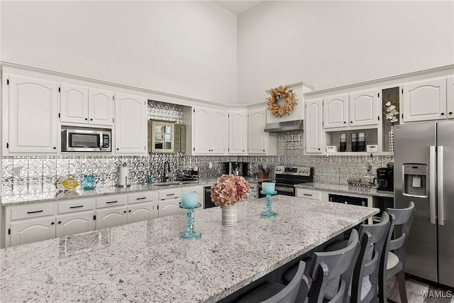 kitchen with white cabinets, light stone countertops, a breakfast bar area, and stainless steel appliances