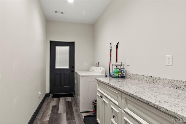 laundry room featuring washing machine and clothes dryer, cabinet space, visible vents, dark wood-type flooring, and baseboards