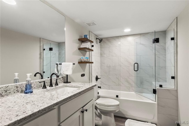 full bath with visible vents, toilet, shower / bath combination with glass door, wood finished floors, and vanity