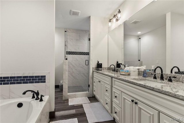 full bath with a stall shower, a garden tub, a sink, and double vanity