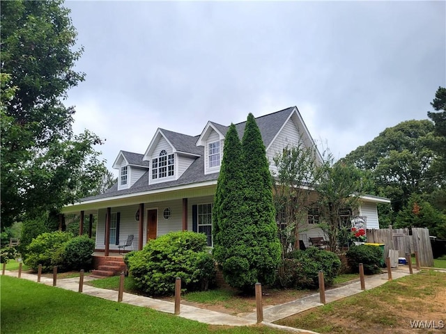 cape cod-style house with covered porch, fence, a shingled roof, and a front yard