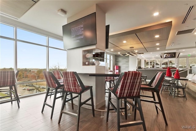 kitchen featuring hardwood / wood-style floors, a notable chandelier, a wall of windows, and a kitchen breakfast bar