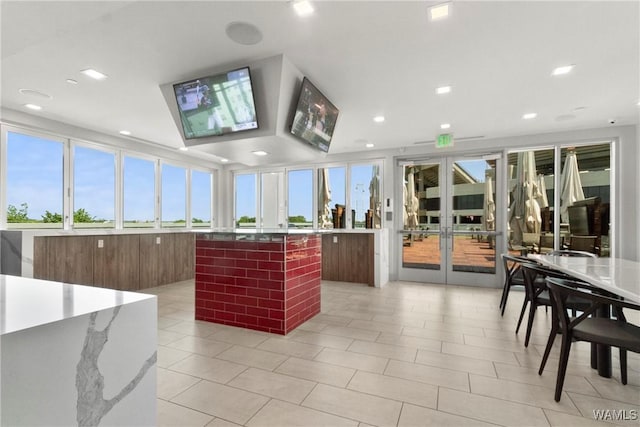 kitchen featuring light tile patterned floors, a center island, a healthy amount of sunlight, and french doors