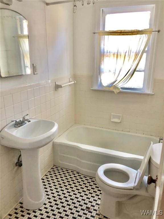 bathroom with tile patterned flooring, toilet, tile walls, and a bathing tub