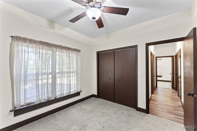 unfurnished bedroom with ceiling fan, light carpet, and a closet