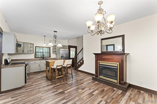 kitchen with stainless steel fridge, gray cabinetry, sink, pendant lighting, and hardwood / wood-style floors