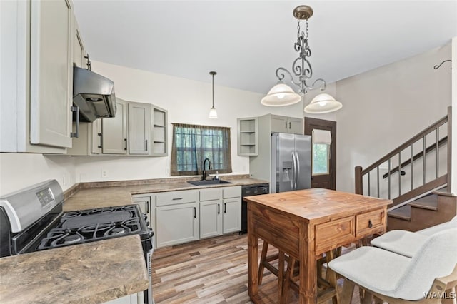 kitchen featuring pendant lighting, black appliances, sink, light wood-type flooring, and extractor fan