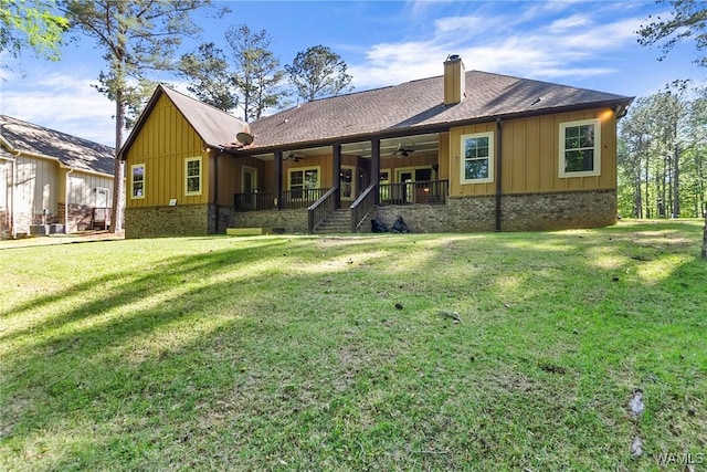 back of property with a chimney, board and batten siding, ceiling fan, a yard, and a shingled roof