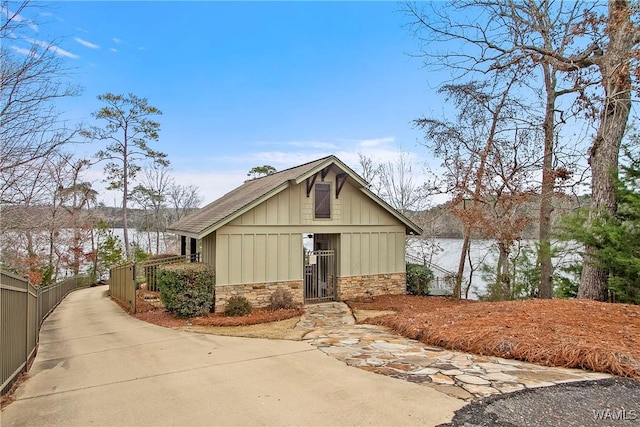 exterior space featuring board and batten siding, fence, and stone siding