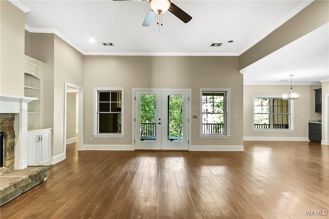 unfurnished living room with visible vents, baseboards, a stone fireplace, wood finished floors, and ceiling fan with notable chandelier