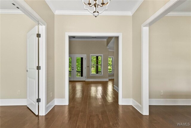 entrance foyer featuring a notable chandelier, baseboards, crown molding, and wood finished floors