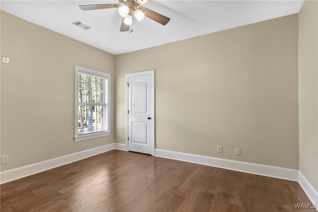 spare room with dark wood finished floors, visible vents, baseboards, and ceiling fan