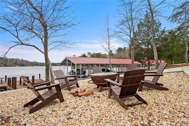 view of patio with a water view, a boat dock, and a fire pit
