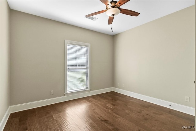 empty room with ceiling fan, visible vents, baseboards, and dark wood finished floors