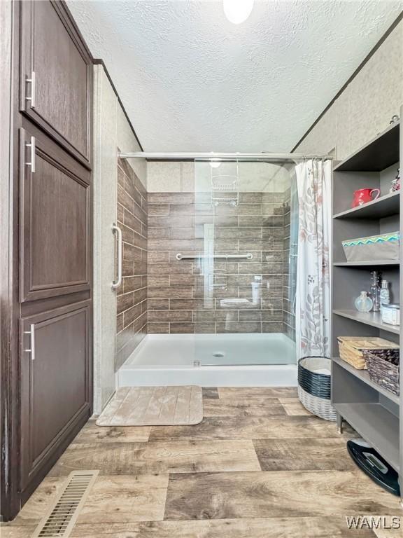 234 Broad Leaf Cir, Moundville, AL 35474 - bathroom featuring a textured ceiling, a shower stall, and wood finished floors