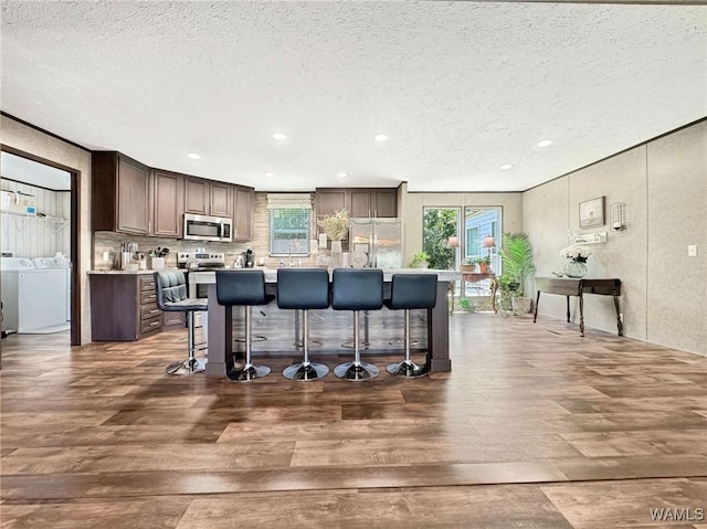 234 Broad Leaf Cir, Moundville, AL 35474 - kitchen featuring appliances with stainless steel finishes, a textured ceiling, dark wood-type flooring, healthy amount of natural light, and a kitchen bar