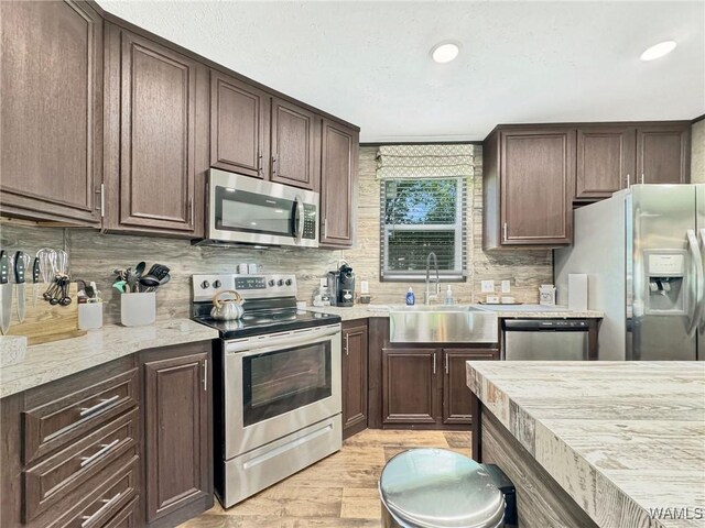 234 Broad Leaf Cir, Moundville, AL 35474 - kitchen featuring appliances with stainless steel finishes, a sink, light wood-style floors, dark brown cabinets, and decorative backsplash