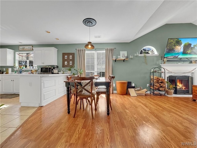 dining area with lofted ceiling and light wood-type flooring