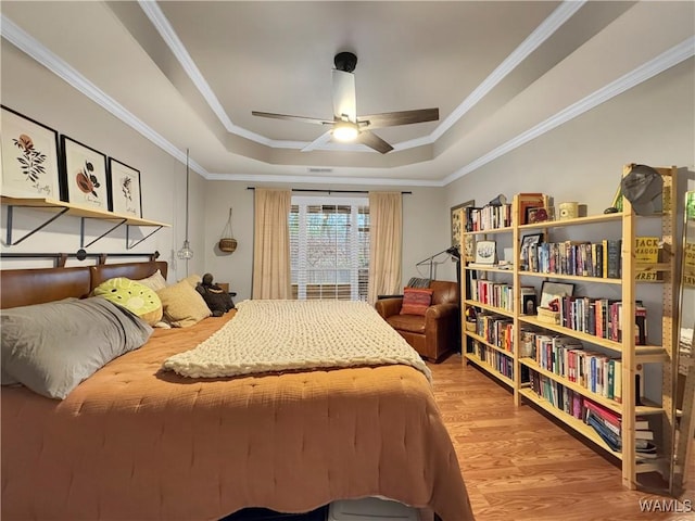 bedroom featuring ceiling fan, crown molding, hardwood / wood-style flooring, and a tray ceiling