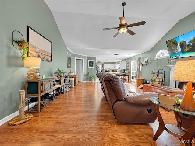 living room with ceiling fan, vaulted ceiling, and light wood-type flooring