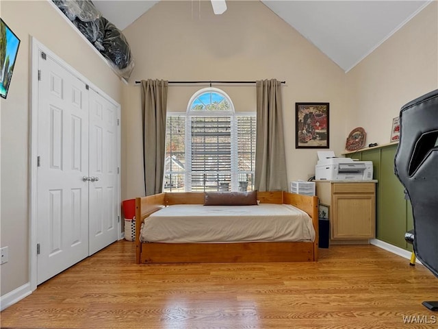 bedroom featuring ceiling fan, a closet, high vaulted ceiling, and light wood-type flooring