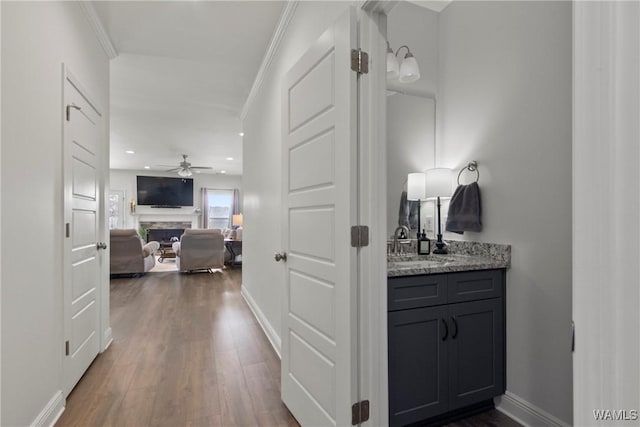 hallway with sink, dark hardwood / wood-style floors, and ornamental molding