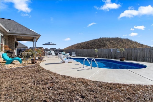 view of swimming pool featuring a patio area, a water slide, a mountain view, and a playground