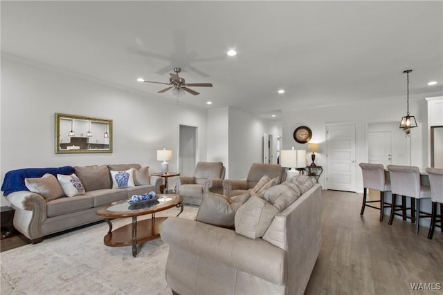 living room featuring ceiling fan, ornamental molding, and wood-type flooring