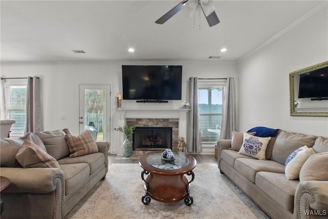 living room featuring light hardwood / wood-style floors, crown molding, ceiling fan, and a fireplace