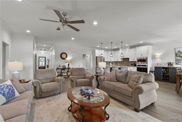 living room featuring ceiling fan, crown molding, and light wood-type flooring