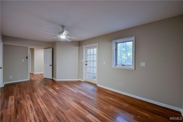 empty room with a ceiling fan, wood finished floors, and baseboards