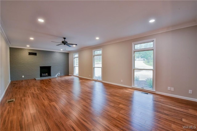 unfurnished living room featuring a wealth of natural light, wood finished floors, and ornamental molding