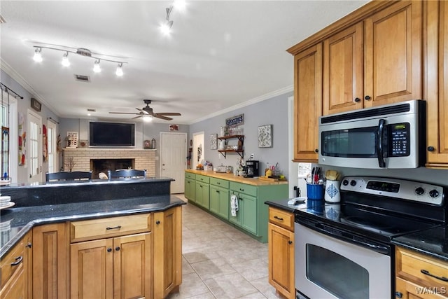 1416 30th Ave E, Tuscaloosa, AL 35404 - kitchen with appliances with stainless steel finishes, ceiling fan, ornamental molding, dark countertops, and a brick fireplace