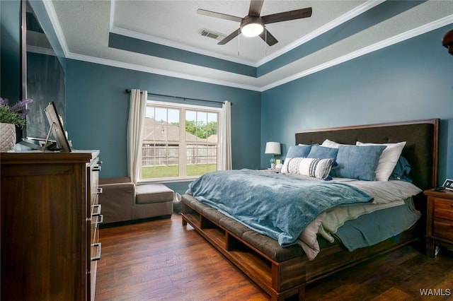bedroom with a tray ceiling, visible vents, crown molding, and hardwood / wood-style flooring