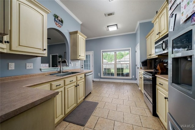 kitchen with cream cabinetry, stainless steel appliances, and a sink