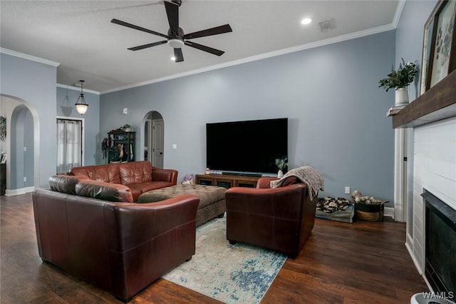 living area with wood finished floors, a ceiling fan, a glass covered fireplace, and arched walkways